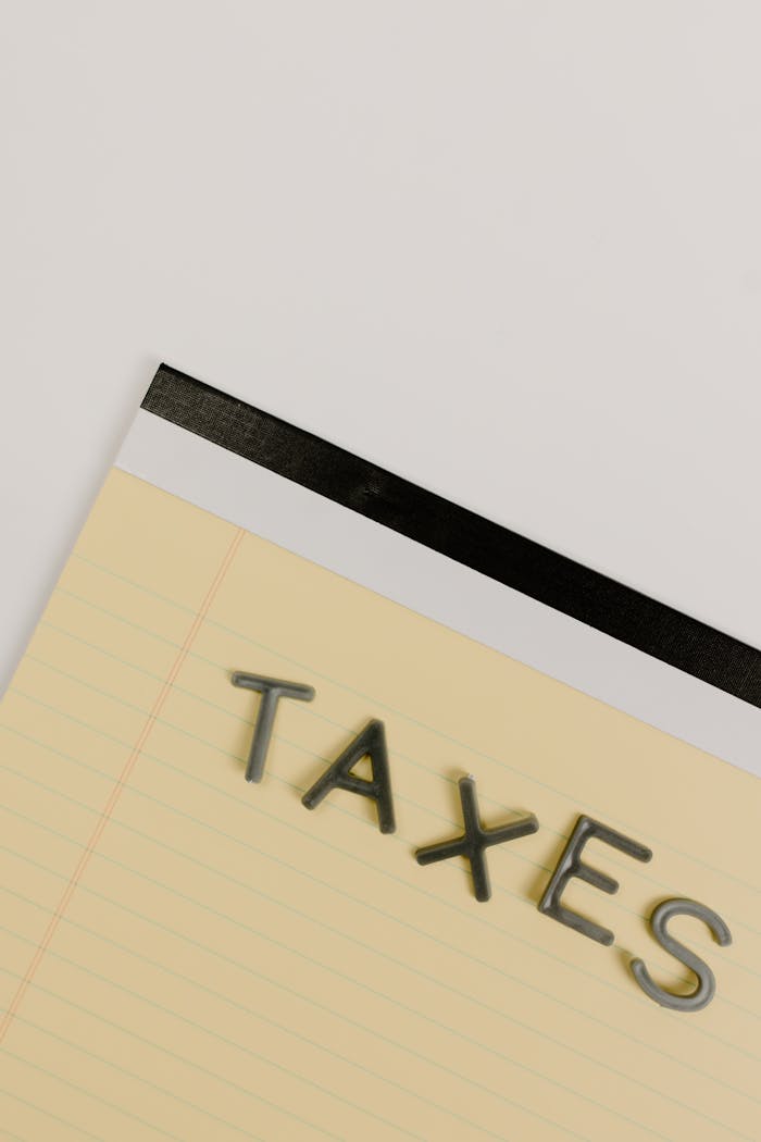 A minimalist image of a notepad displaying the word TAXES on a white background.