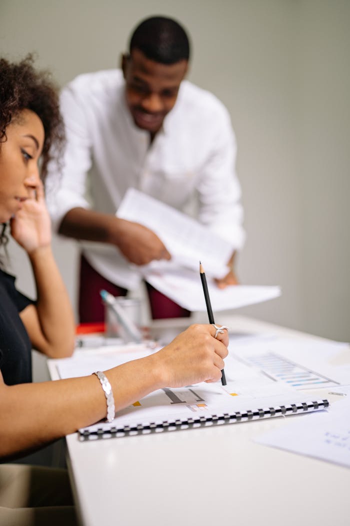 Two adults working together at a desk in a modern office setting, engaged in planning.